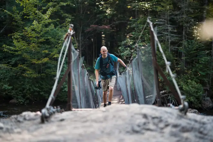 A man walks across a wooden bridge.