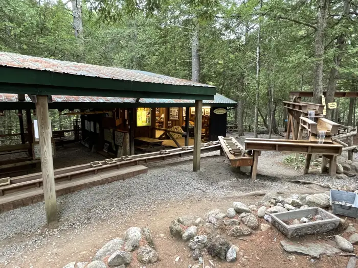 An outdoor wooden sluice in front of a covered &quot;gem mining&quot; activity for children.