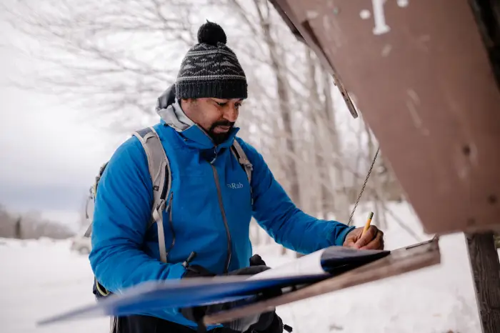 A hiker signing in at a trailhead before a winter hike.