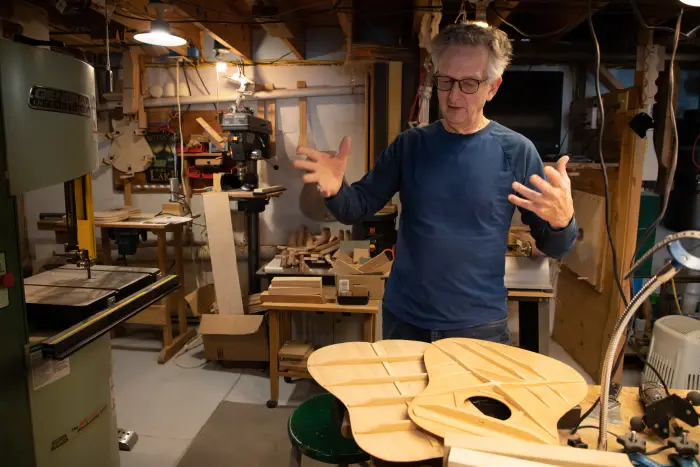 a man looks over the pieces of a guitar he's making.