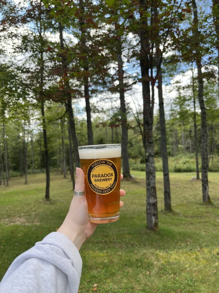 A person's hand holds a paradox brewery beer in a paradox brewery glass