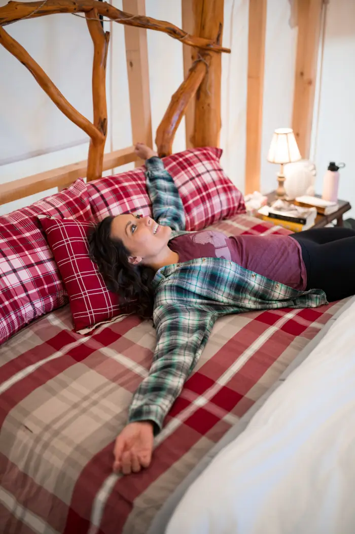 A woman lays on a plaid bed.