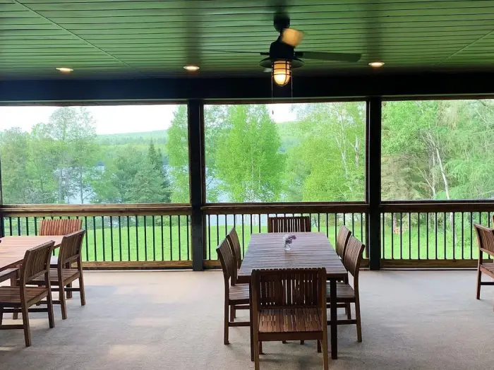 Tables with a view on the screened porch at Lake Harris Lodge.