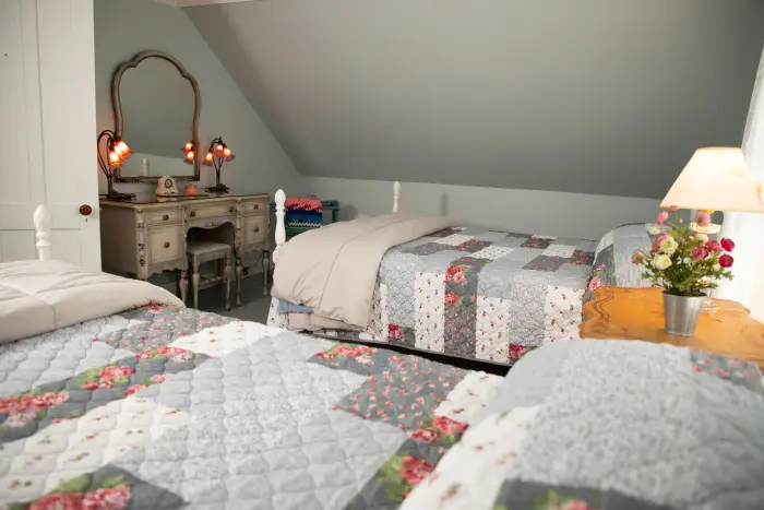 two floral twin beds in a grey dollhouse-style room.