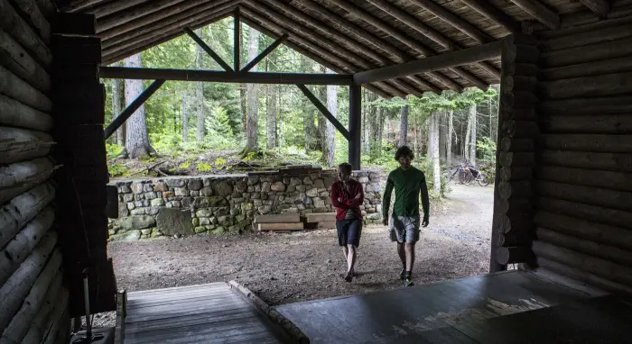 Two visitors walk towards a ramp entrance at Camp Santanoni