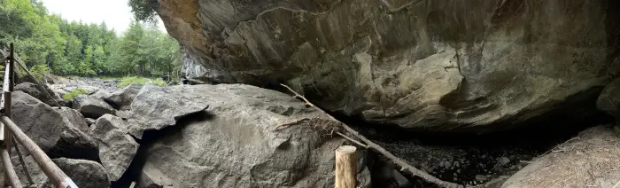 a field of rocks and pebbles lead into a dark cave.