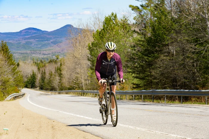 A woman bikes up a roadside hill.