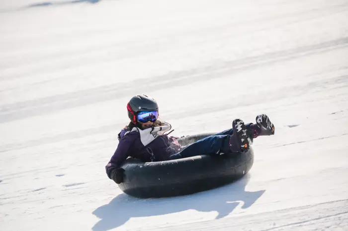 A young girl tubing down a snowy hill.