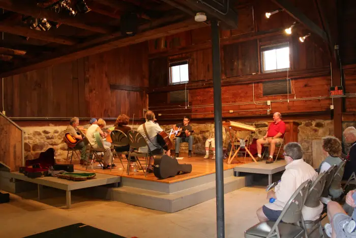 A guitar ensemble performs for an audience in a dark performance hall.