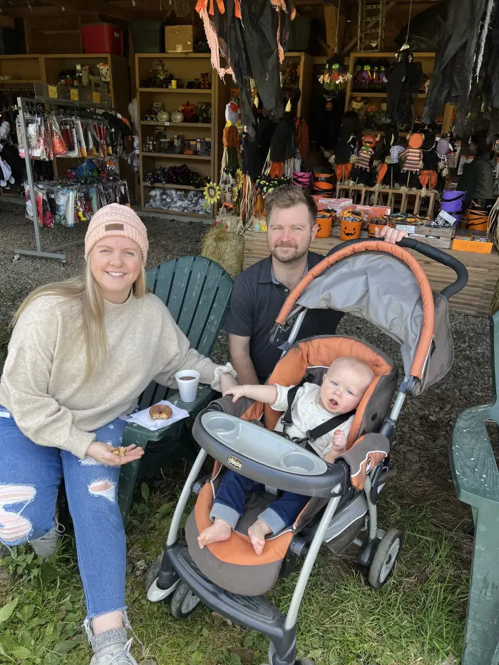 A woman&#44; man and a baby in a stroller pose with cinnamon sugar donuts.