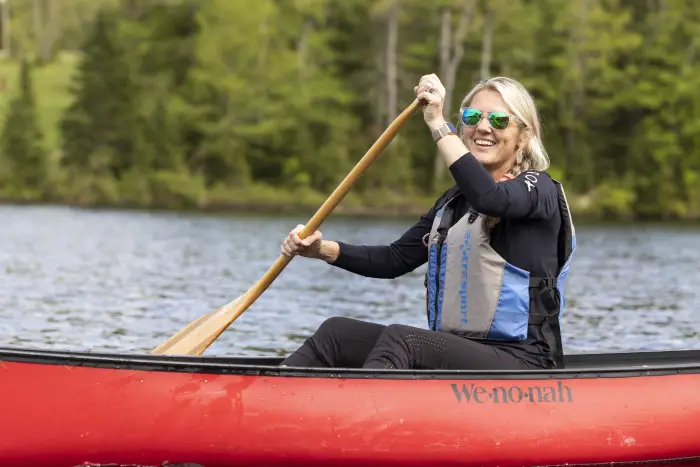 a woman paddles in a canoe on the water.