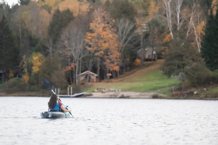 A woman paddles a kayak towards shore.