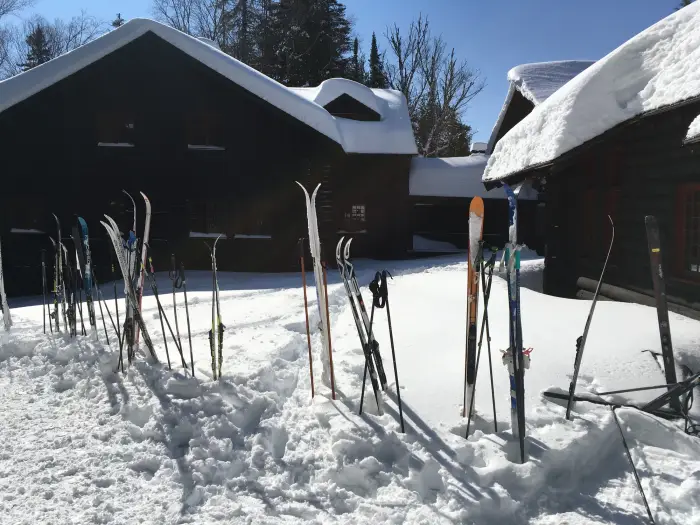 Skis stick up out of the snow in front of a snow-covered lodge.