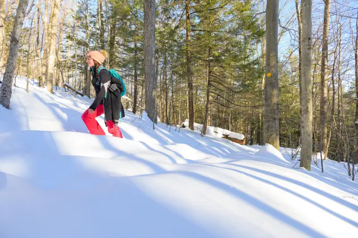 A woman hikes up a mountain in heavy powdered snow.