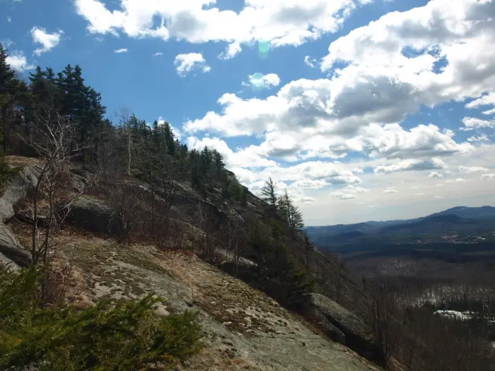 Looking outward from a mountain ride&#44; with sloping rocks on the left and views of other mountains to the right.