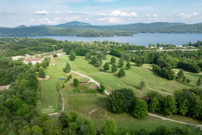 An aerial view of the Schroon Lake Golf Course with well manicured fairways and the lake in the background.