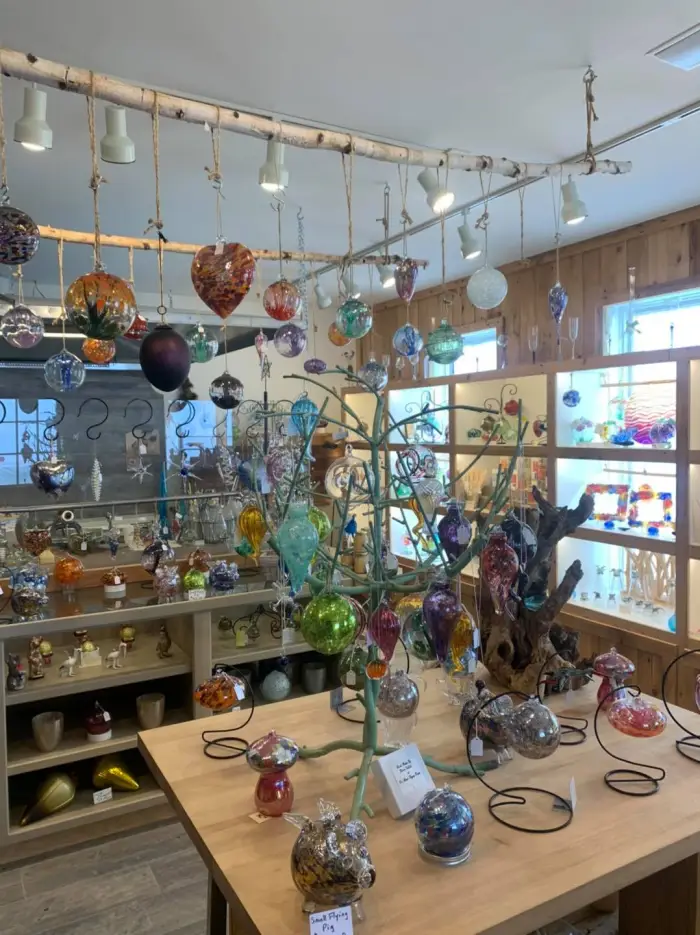 A colorful display of art glass objects on shelves and hanging in a small shop.