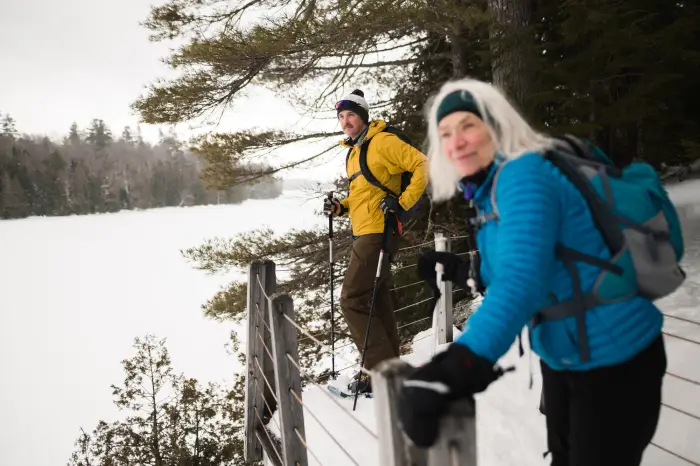 Two hikers look out on an icy lake.