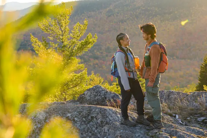 A man and woman look at each other after a fall hike.