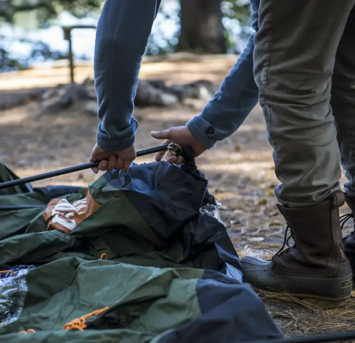 Someone setting up a tent with poles