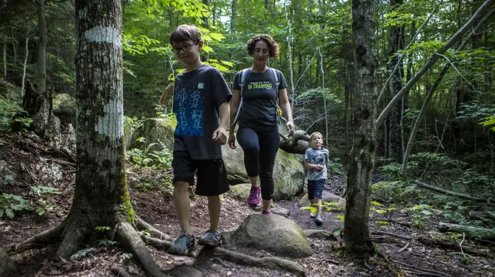 A woman walks a hiking trail with her two sons.