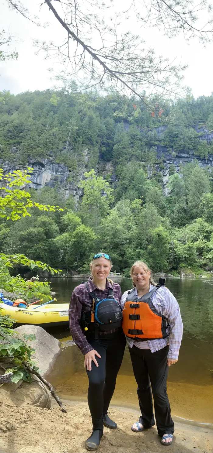 mother and daughter in front of raft and towering cliffs behind