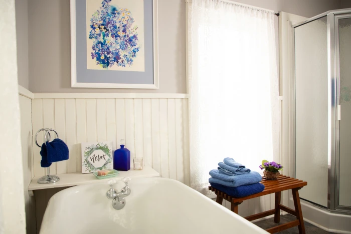 The Inn at Santanoni a bath tub decorated with blue towels and bottles with a wooden stool next to it.