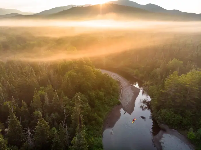 Paddling on the Opalescent River at sunrise with mountains in the background