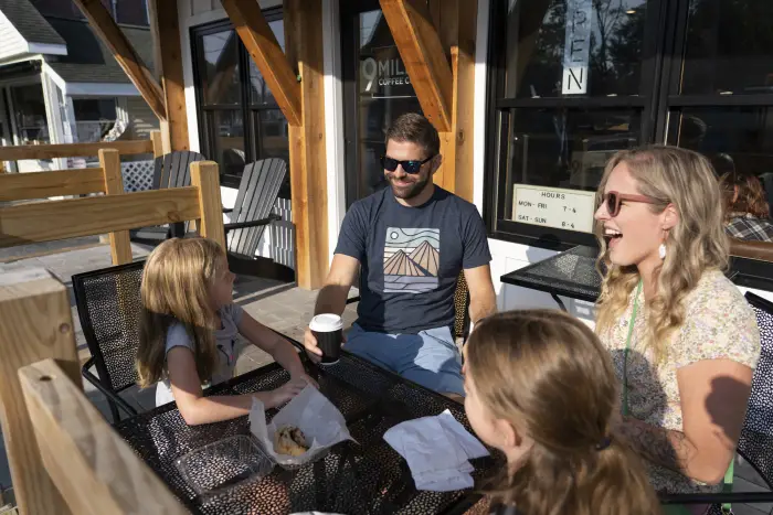 Two adults and two children sit at a table at an outdoor restaurant.