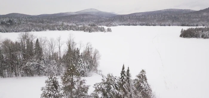 An aerial view of a wintery landscape and snow covered lake.