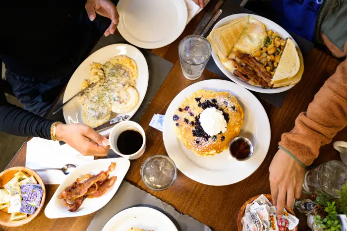 a table set with coffee&#44; blue berry pancakes&#44; homefries&#44; eggs&#44; and other breakfast foods.