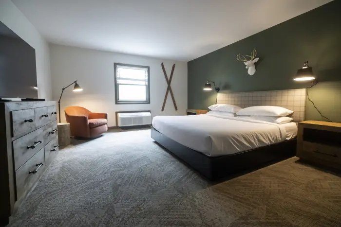 A hotel room with Adirondack inspired decor&#44; including wooden skis on the wall.