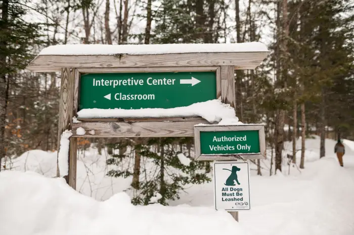 interpretive center sign pointing to a hiker walking down the trail.