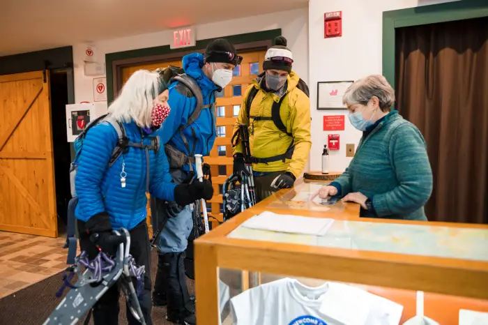 Three people in outdoor gear look at a map with an interpretive center staff member.