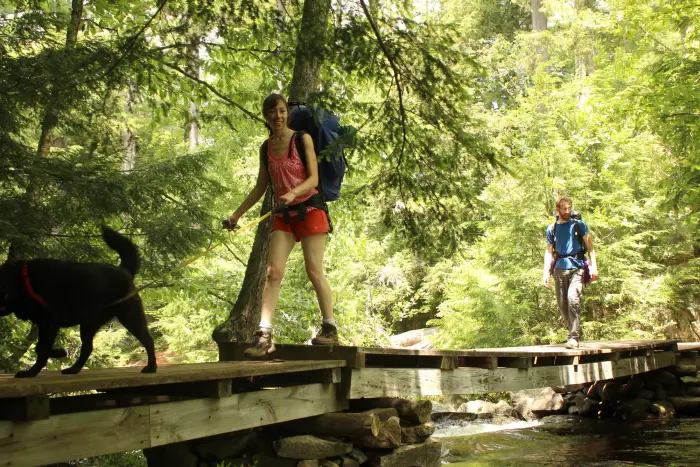 Two people walk across a wooden bridge