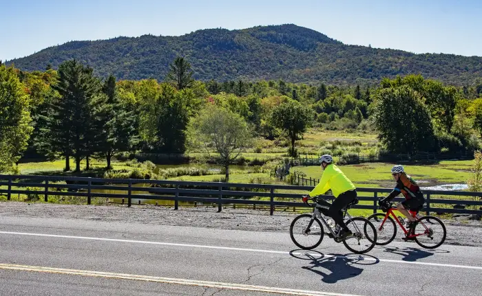 Two riders glide past rolling hills during fall