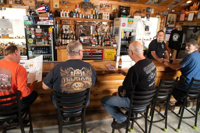 A group of men sit at a fully stocked rustic bar.