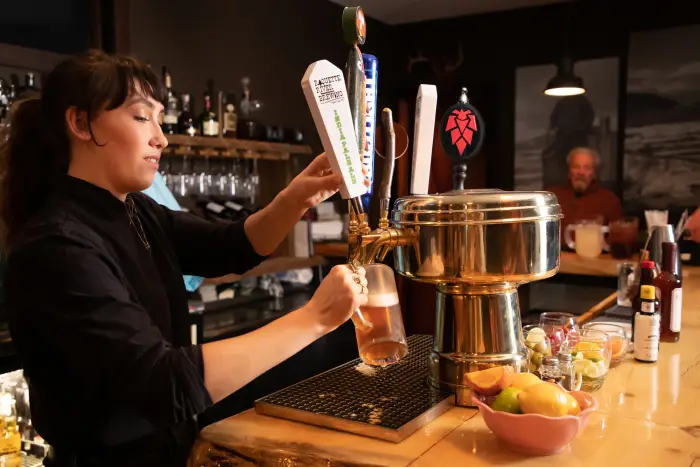 A woman fills a glass with Raquette River Brewing beer.