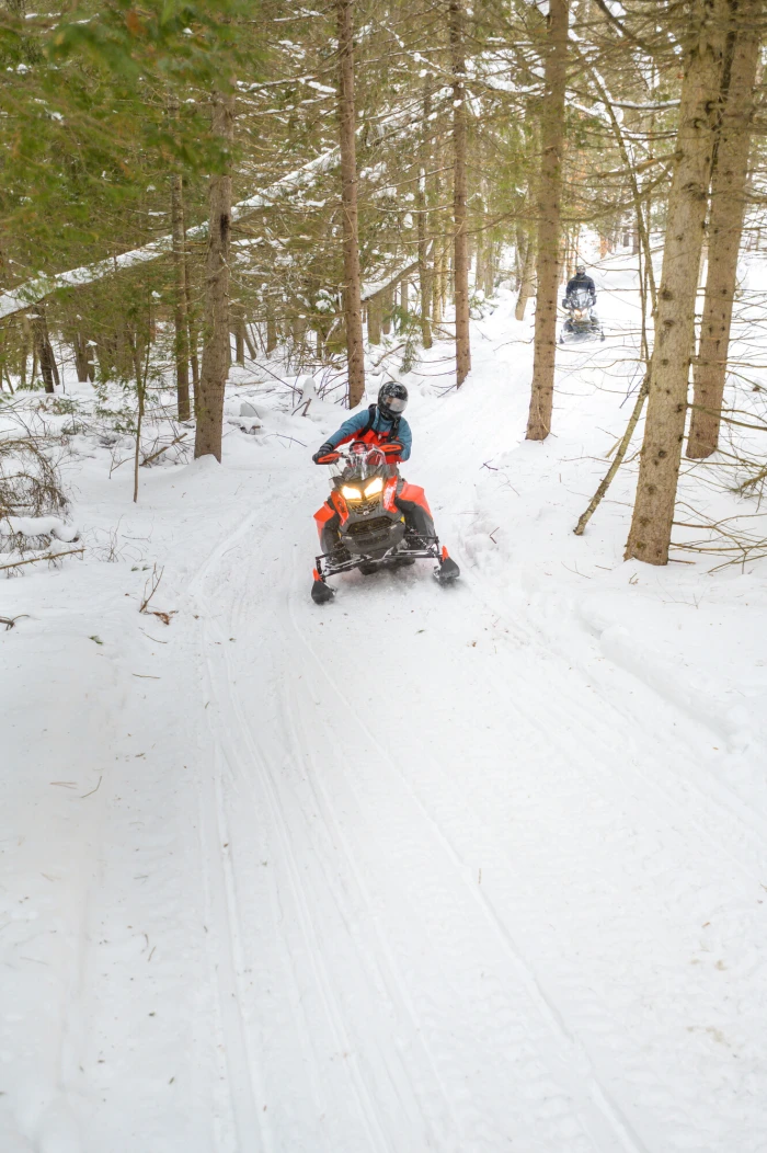 A person rides a snowmobile along a snowy trail