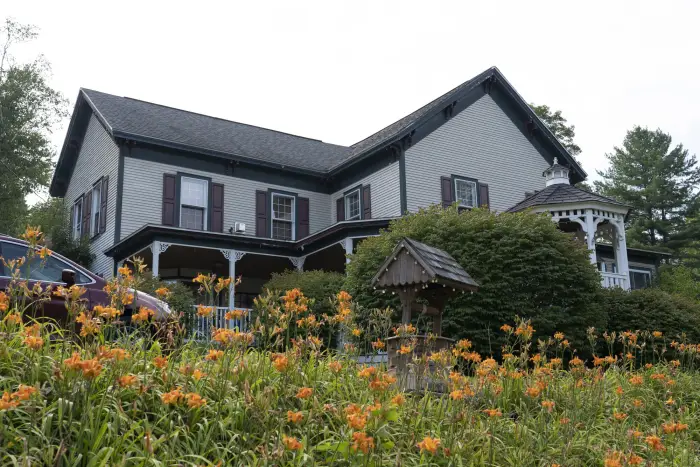 A grey multi-level home with orange flowers in front.