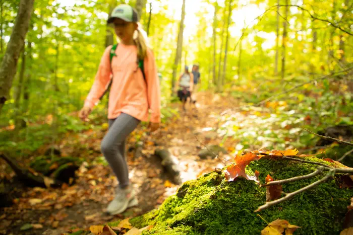 Young girl leads a family on a fall hike.