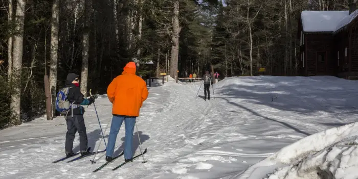 A few people ski and snowshoe on a wide trail