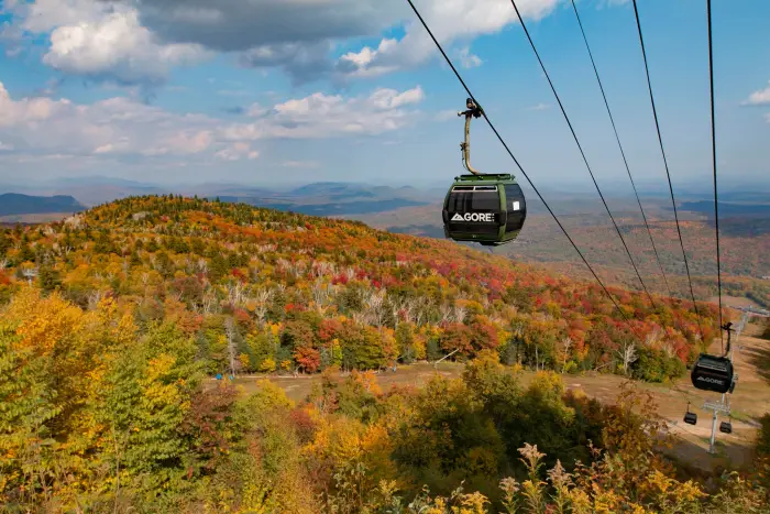 Gondolas in operation at Gore Mountain in the fall&#44; with a backdrop of mountains adorned in seasonal fall foliage