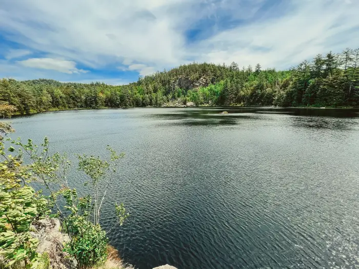 A view from a cliff of a pond with another sheer cliff on the opposite shore.