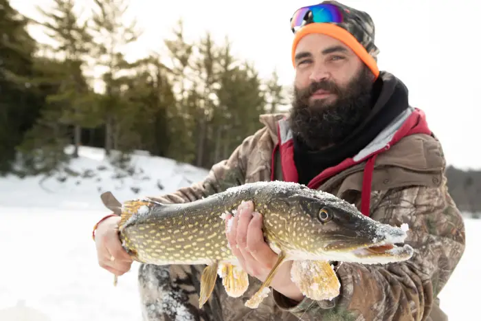 An ice fisherman holding his prize catch.