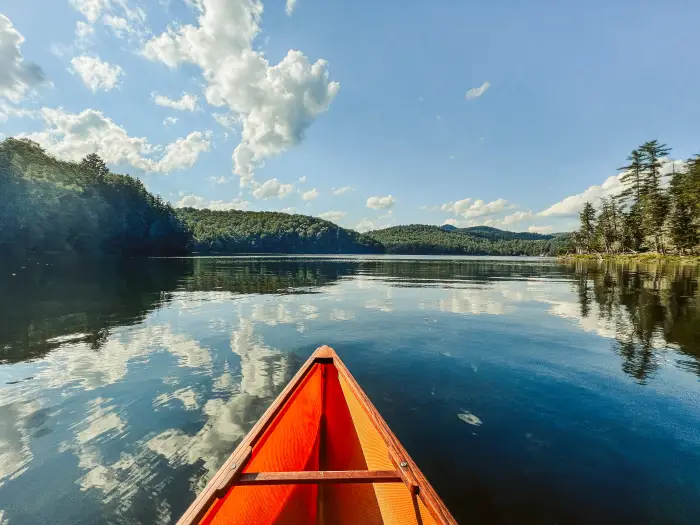 The bow of a canoe pointing out into an Adirondack lake with mountain views