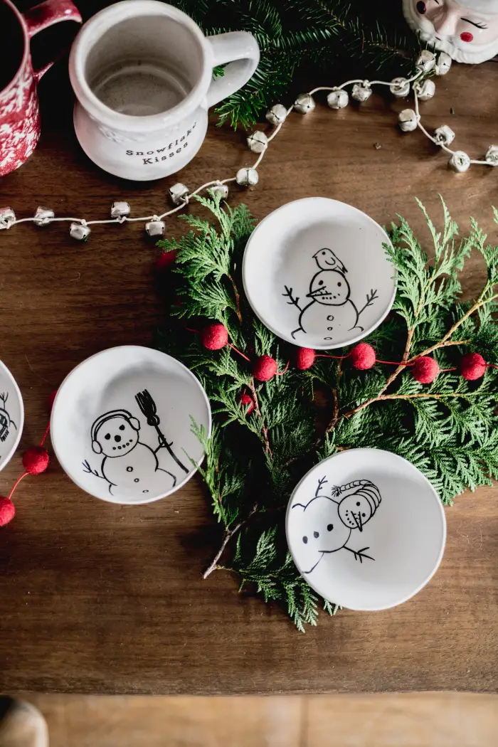 Looking down at a festive wood table decorated with snowman themed plates and pine boughs.