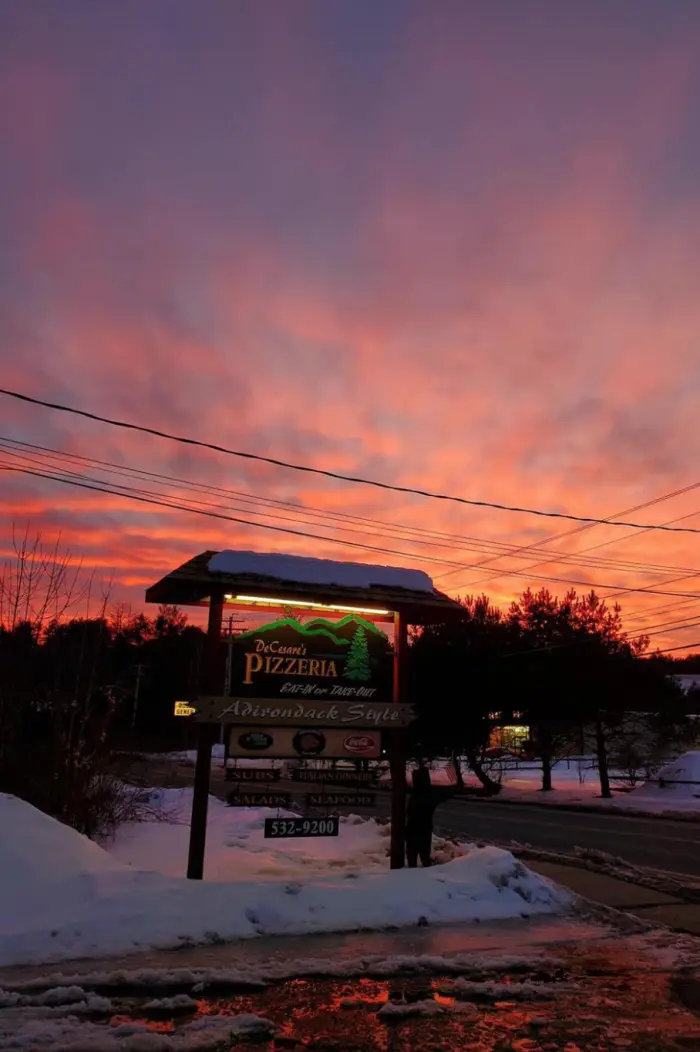 The DeCesare's Pizzeria sign during the winter with a beautiful sunset backdrop.