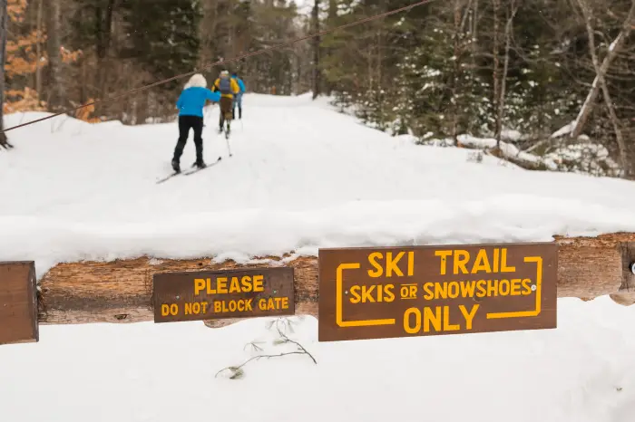 A sign blocking a snowy trail for skiers and snowshoers only.