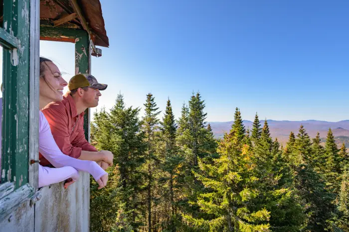 a man and a woman look out from the observation deck of a fire tower
